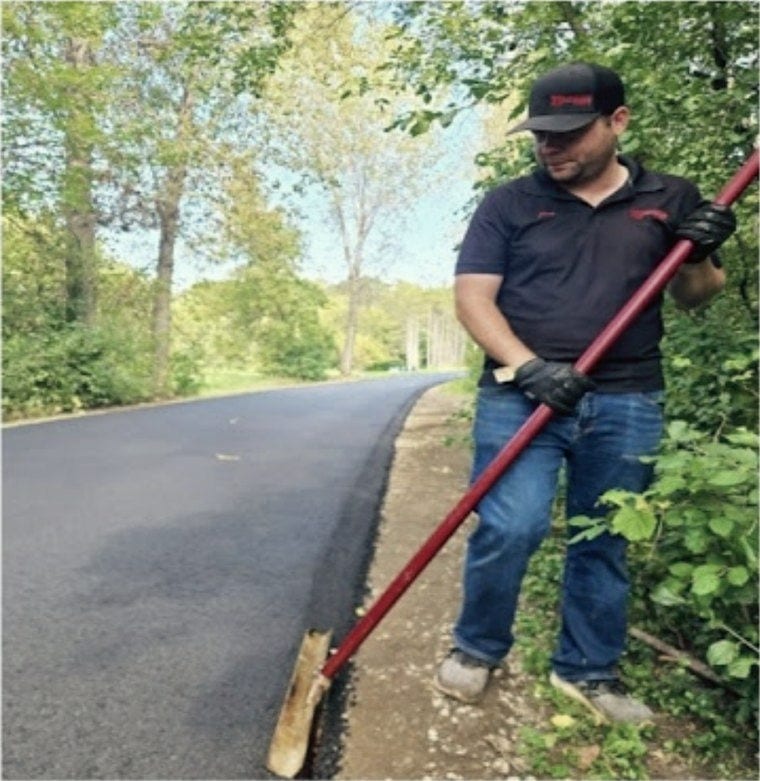 One of the crew with a rake, working the edge of the finished mat.